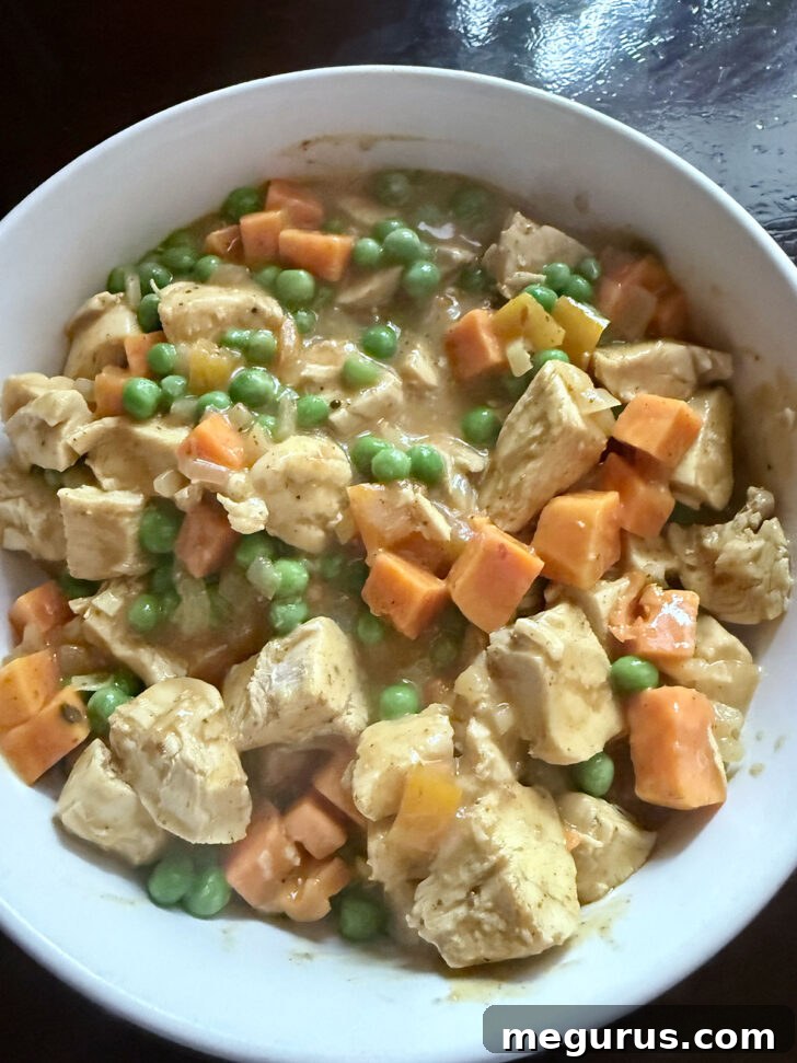 Finished curried chicken filling in a bowl, ready for cooling.