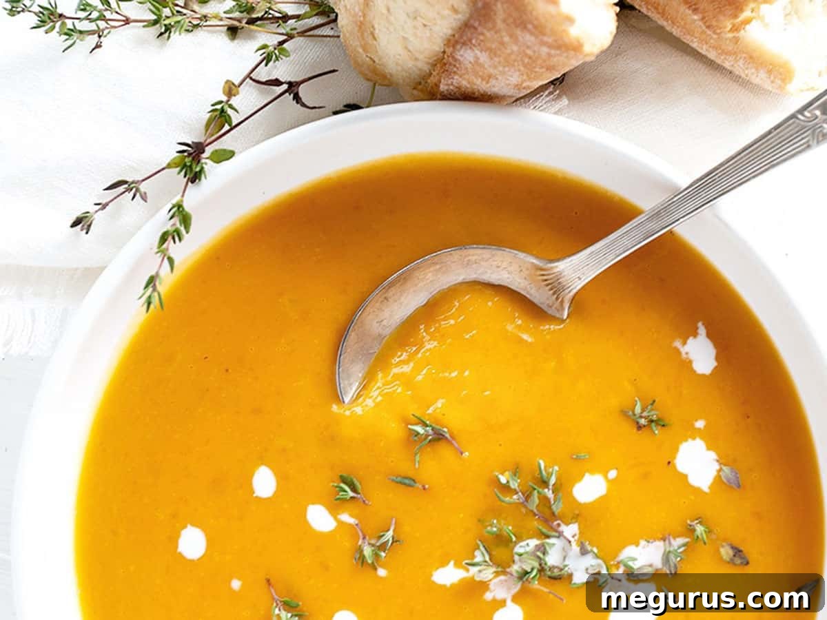 Creamy roasted butternut squash soup in a white bowl, garnished with cream swirls and fresh thyme
