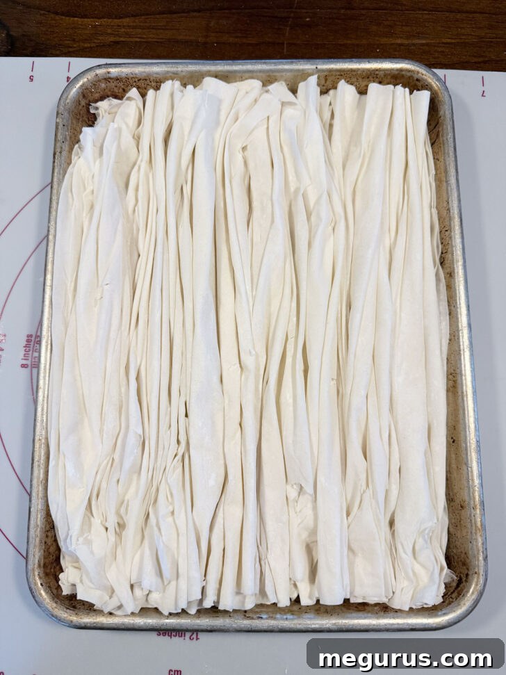 The baking sheet completely filled with folded phyllo pastry sheets, ready for baking.