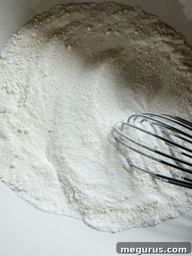 A bowl with flour and sugar being whisked together, preparing the base for the rhubarb custard filling.