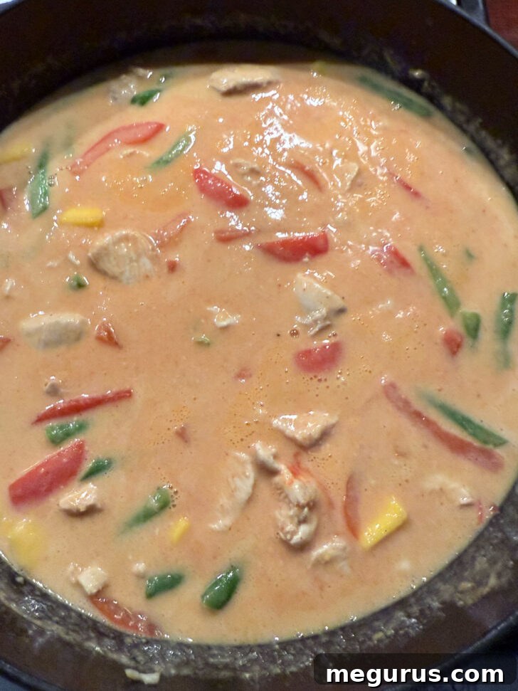 The finished Thai mango chicken curry, vibrant and aromatic, ready to be served directly from the skillet.