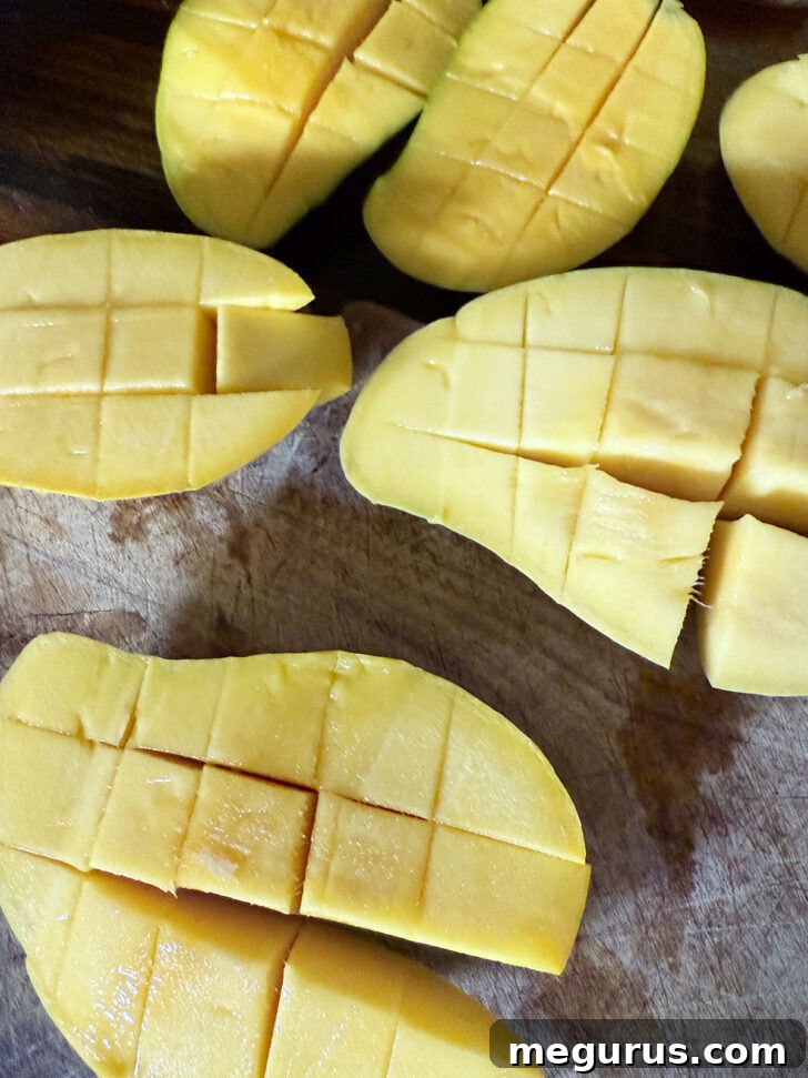 Fresh, ripe Ataulfo mangoes being carefully cut into perfect cubes on a clean cutting board.