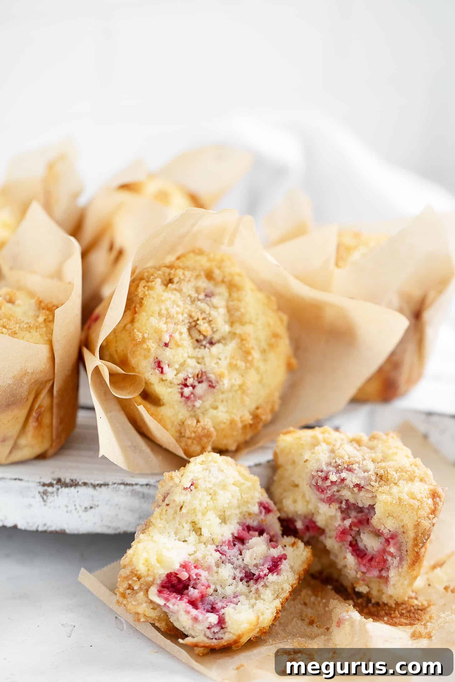 Raspberry lemon muffins on serving board, showcasing their golden crumb and fluffy interior.