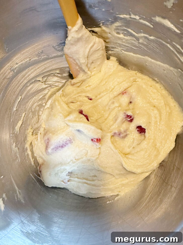 Raspberry lemon muffin batter after folding in the raspberries, with visible fruit.
