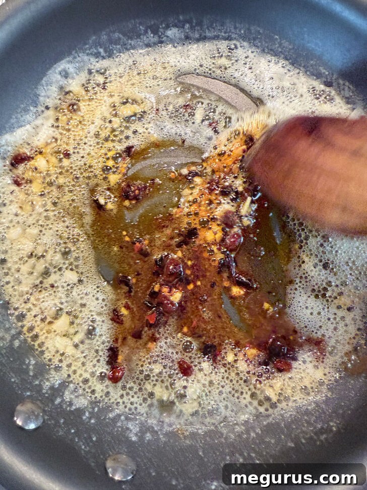 Adding chili crisp to melted butter in skillet.