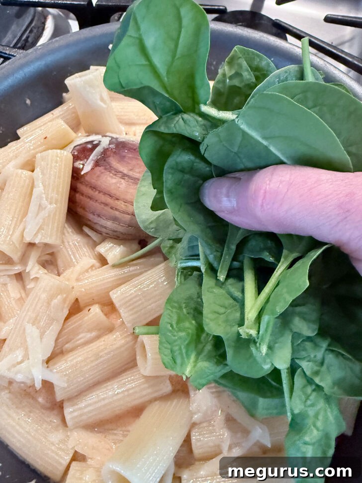 Adding fresh spinach to the skillet.