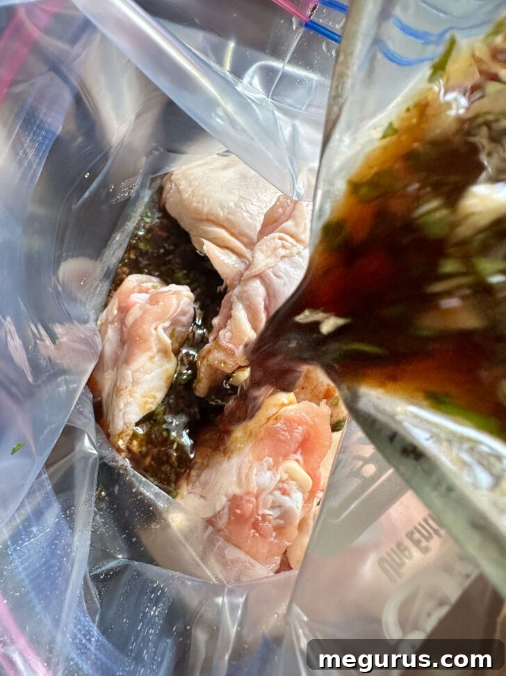 Adding the freshly mixed marinade to a plastic zipper bag containing chicken thighs, ready for flavor infusion.
