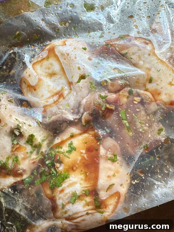 Sealed plastic zipper bag with chicken thighs submerged in marinade, ready for refrigeration and flavor absorption.