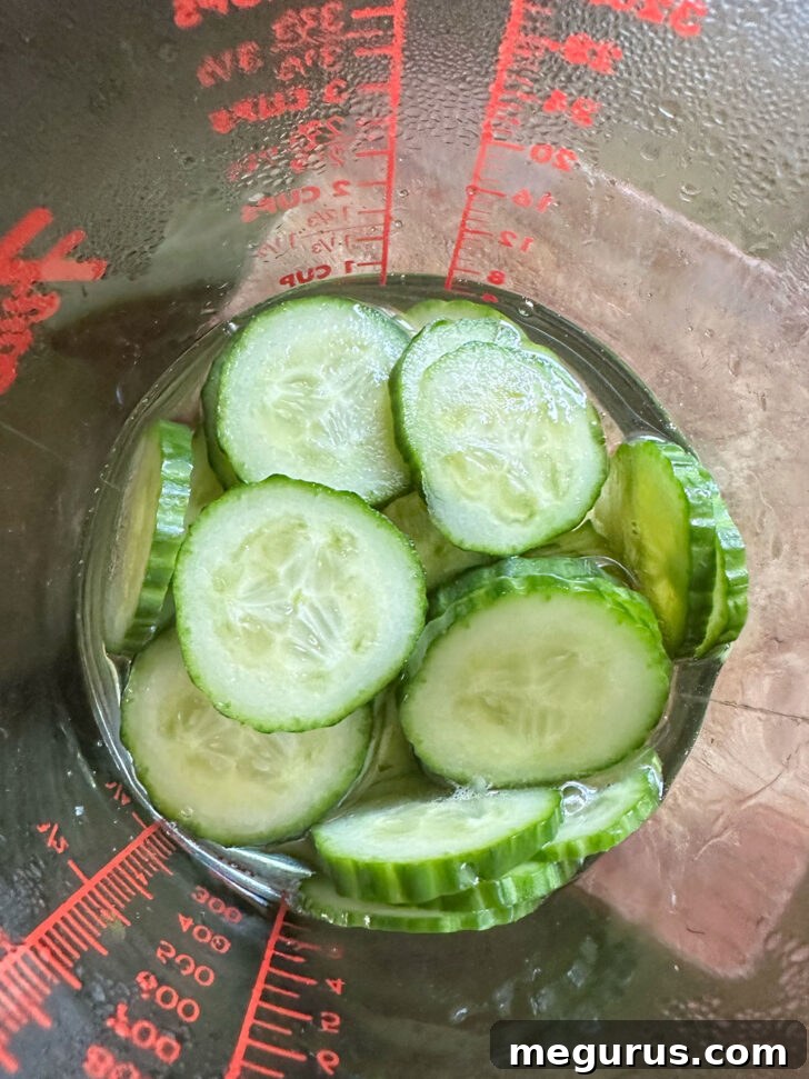 Fresh cucumber slices marinating in a clear measuring cup for a quick and refreshing side dish.