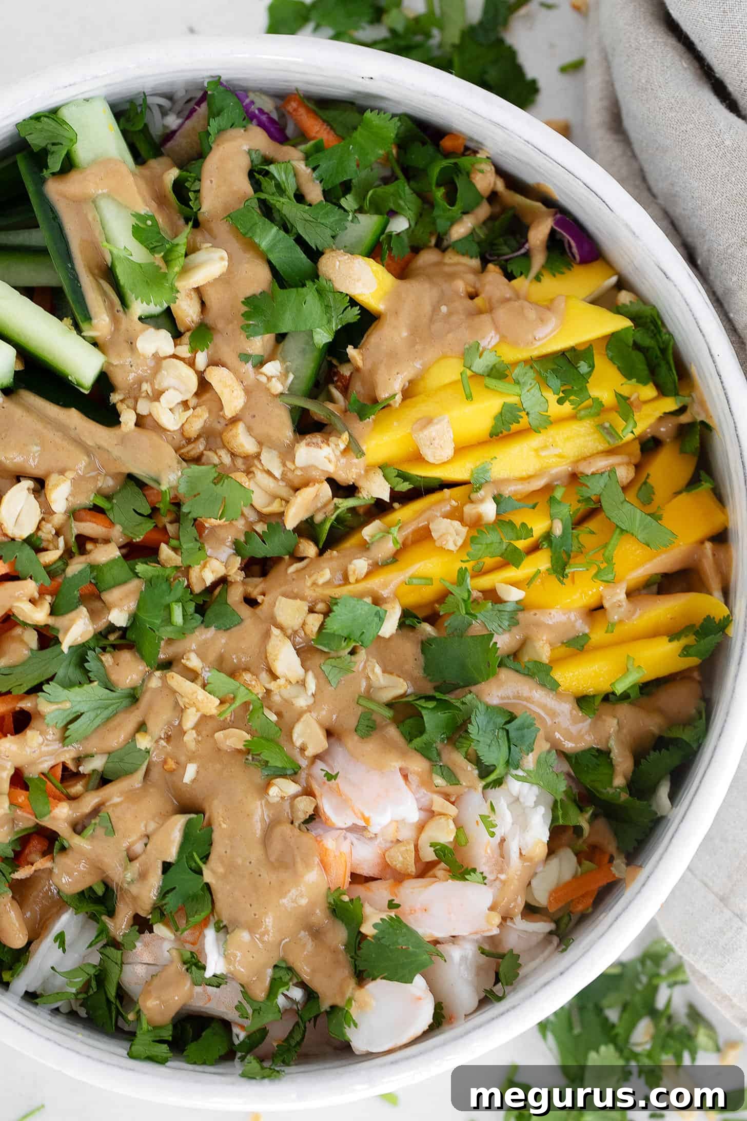 A large serving bowl filled with Summer roll salad, with the dressing drizzled over the top, ready to be tossed.