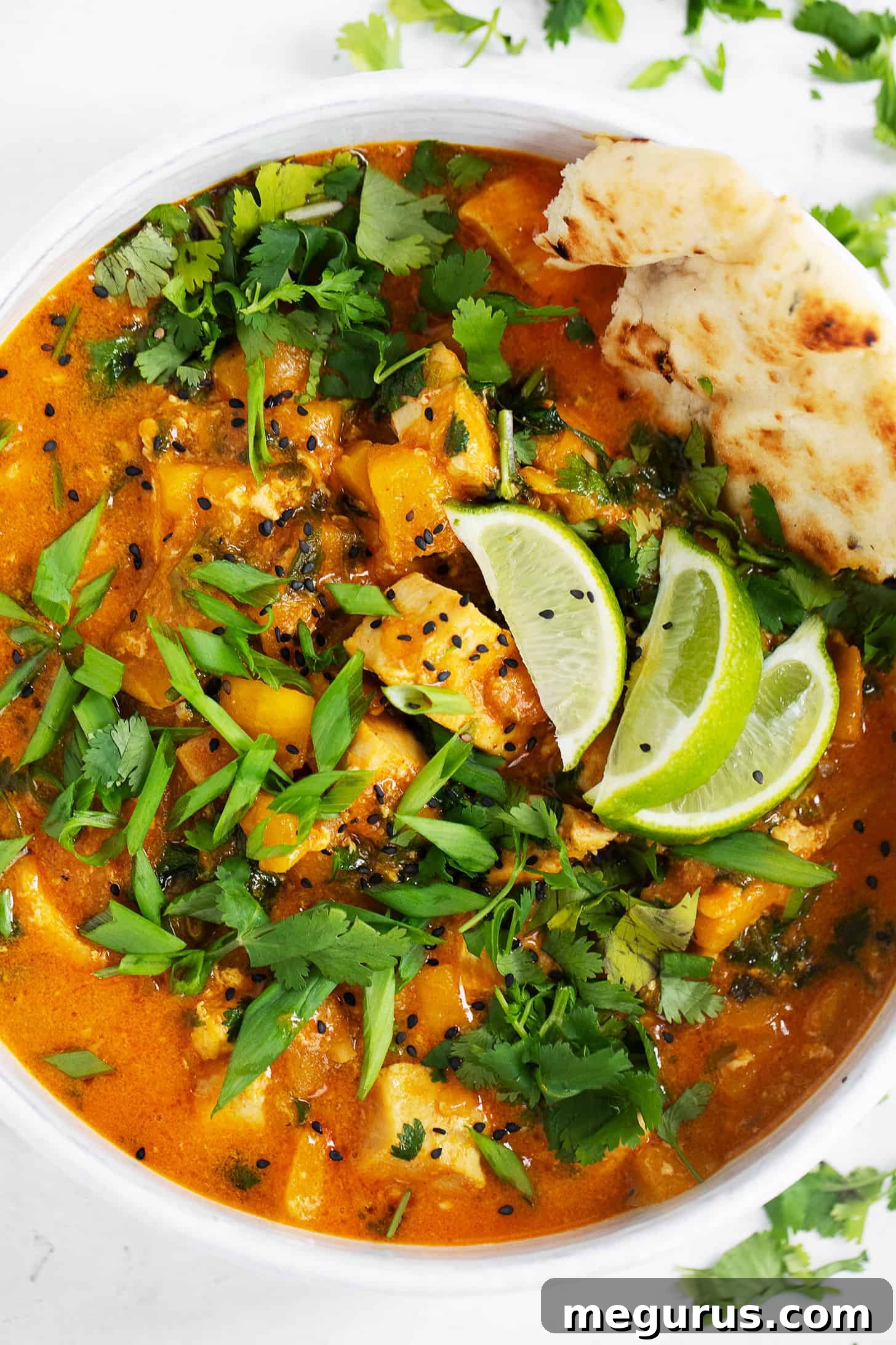 Chicken mango curry in serving bowl with limes.