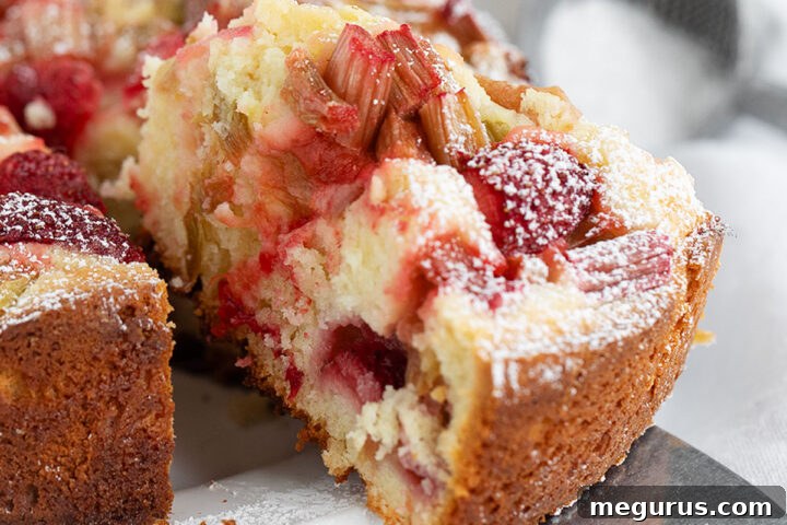Strawberry rhubarb cake sliced on serving plate.