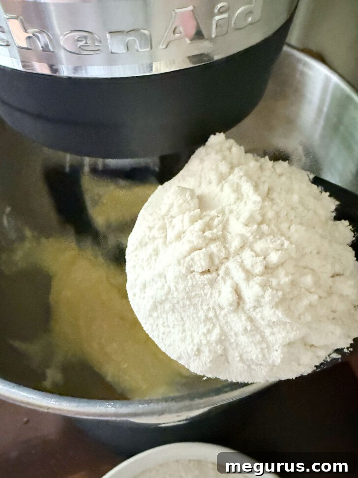 Adding all-purpose flour to the cake batter in a stand mixer.