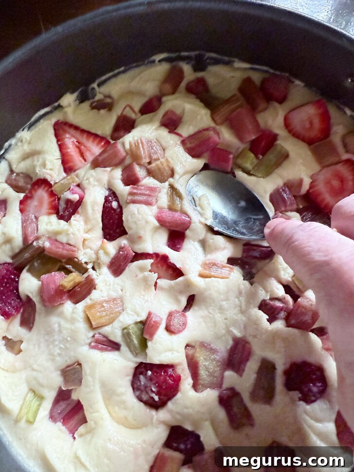 Pressing the fruit into the cake batter with the back of a spoon.