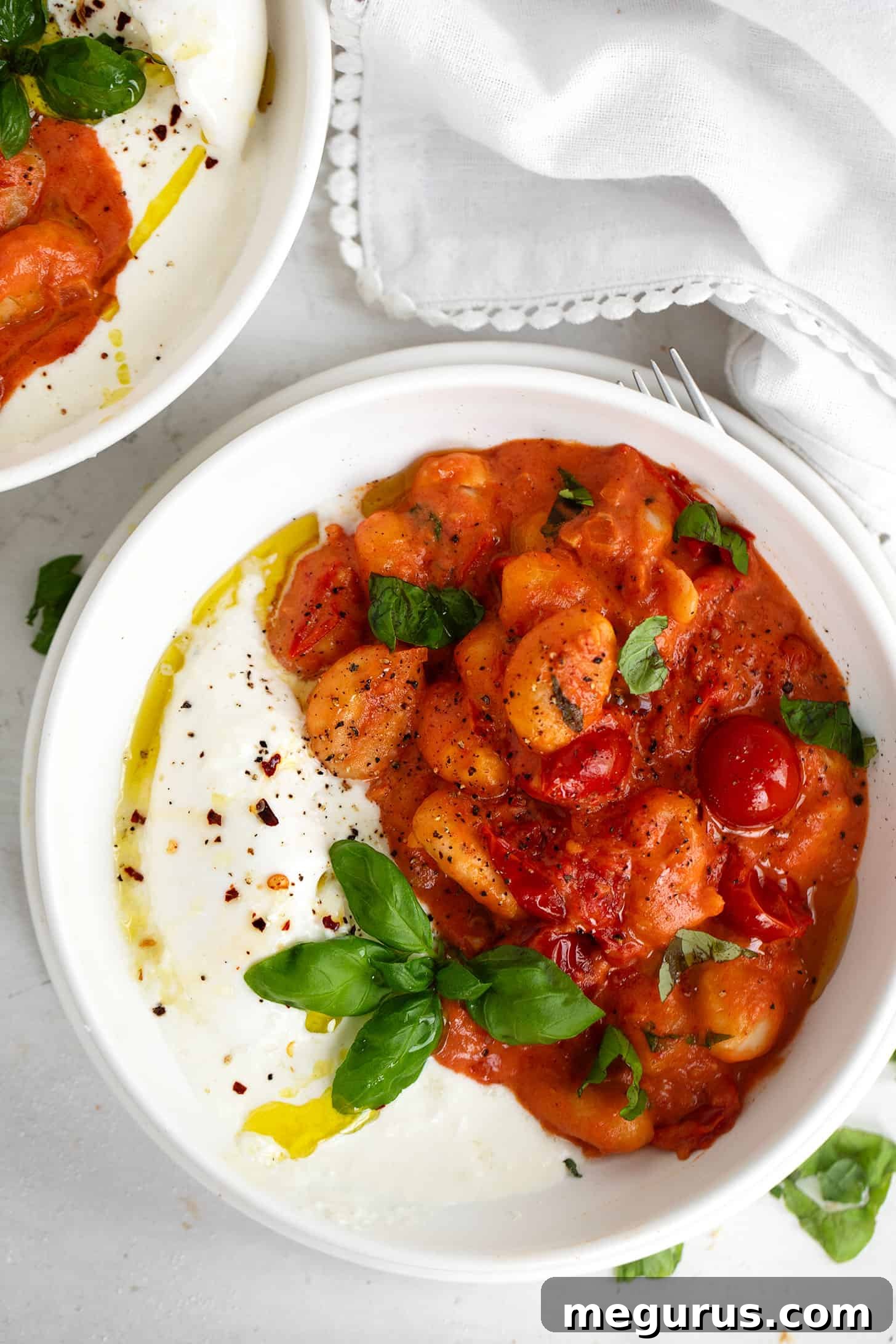 A close-up of Gnocchi Burrata in a serving bowl, showcasing the creamy burrata melting into the tomato sauce with fresh basil.