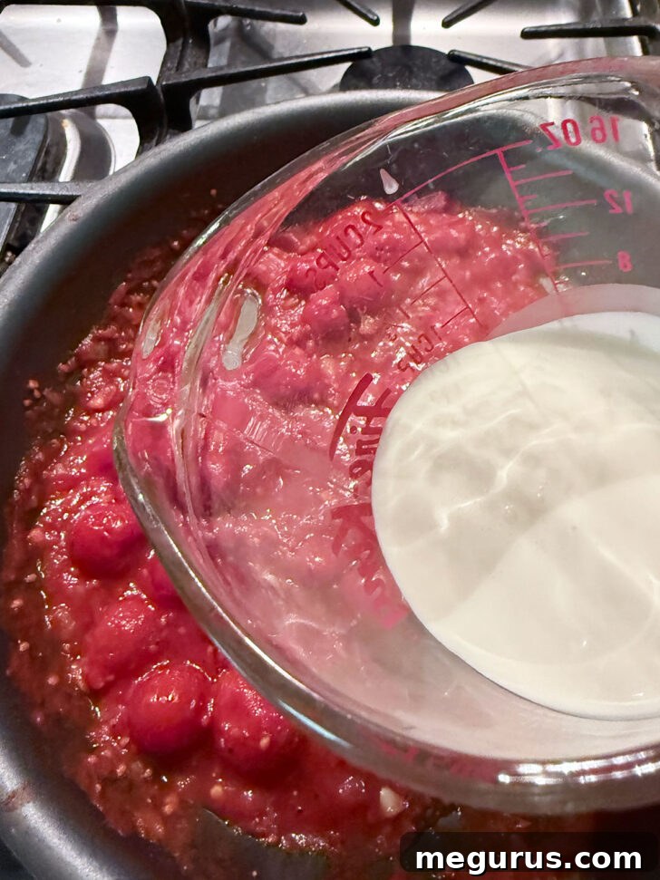 Adding cream to the skillet with the tomatoes.