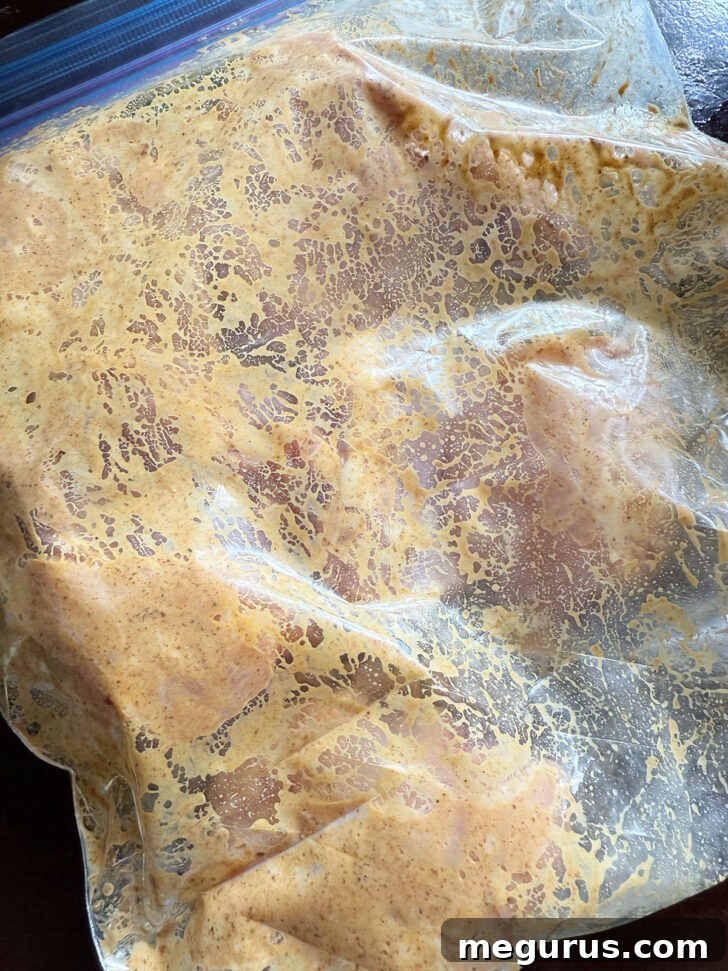 Chicken coated with marinade in a zipper bag.