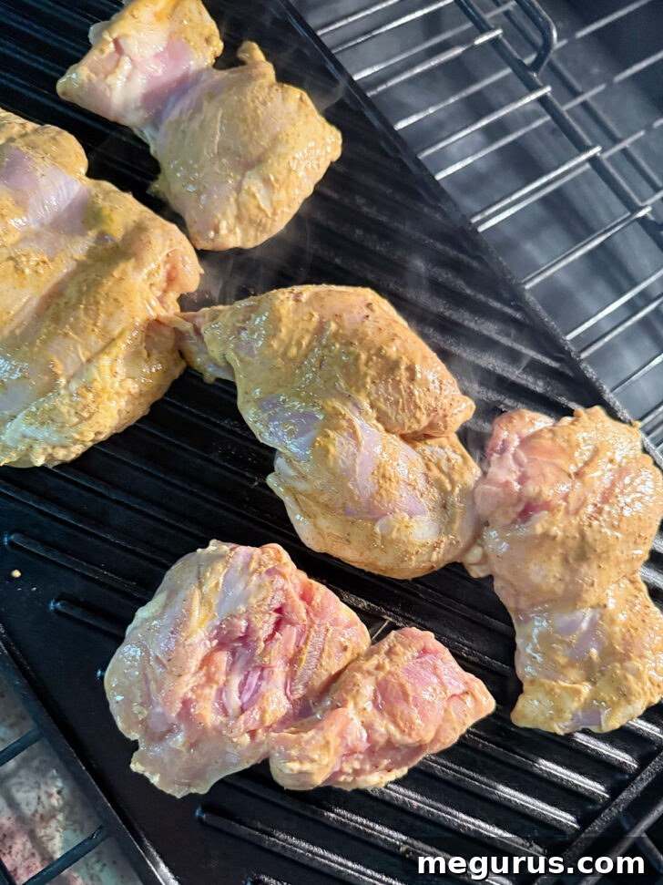 Marinated chicken cooking on a grill pan in the oven.