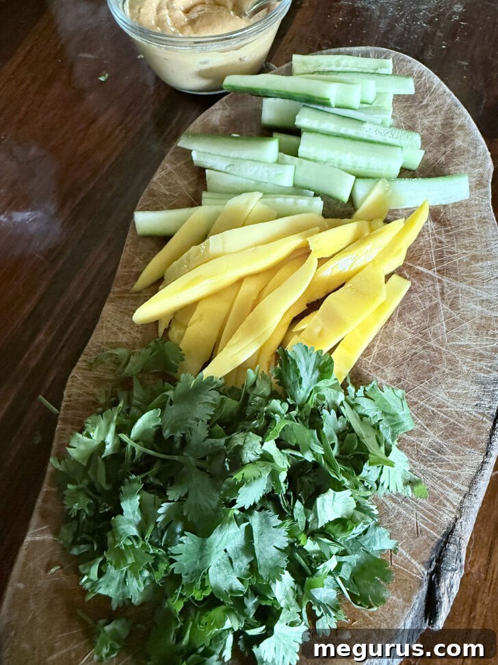 Prepped cucumber, mango, and cilantro on a cutting board.