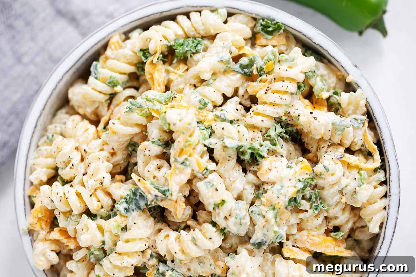 A vibrant bowl of Jalapeño Popper Pasta Salad, showcasing the creamy dressing, pasta, and hints of cheese and roasted jalapeños.