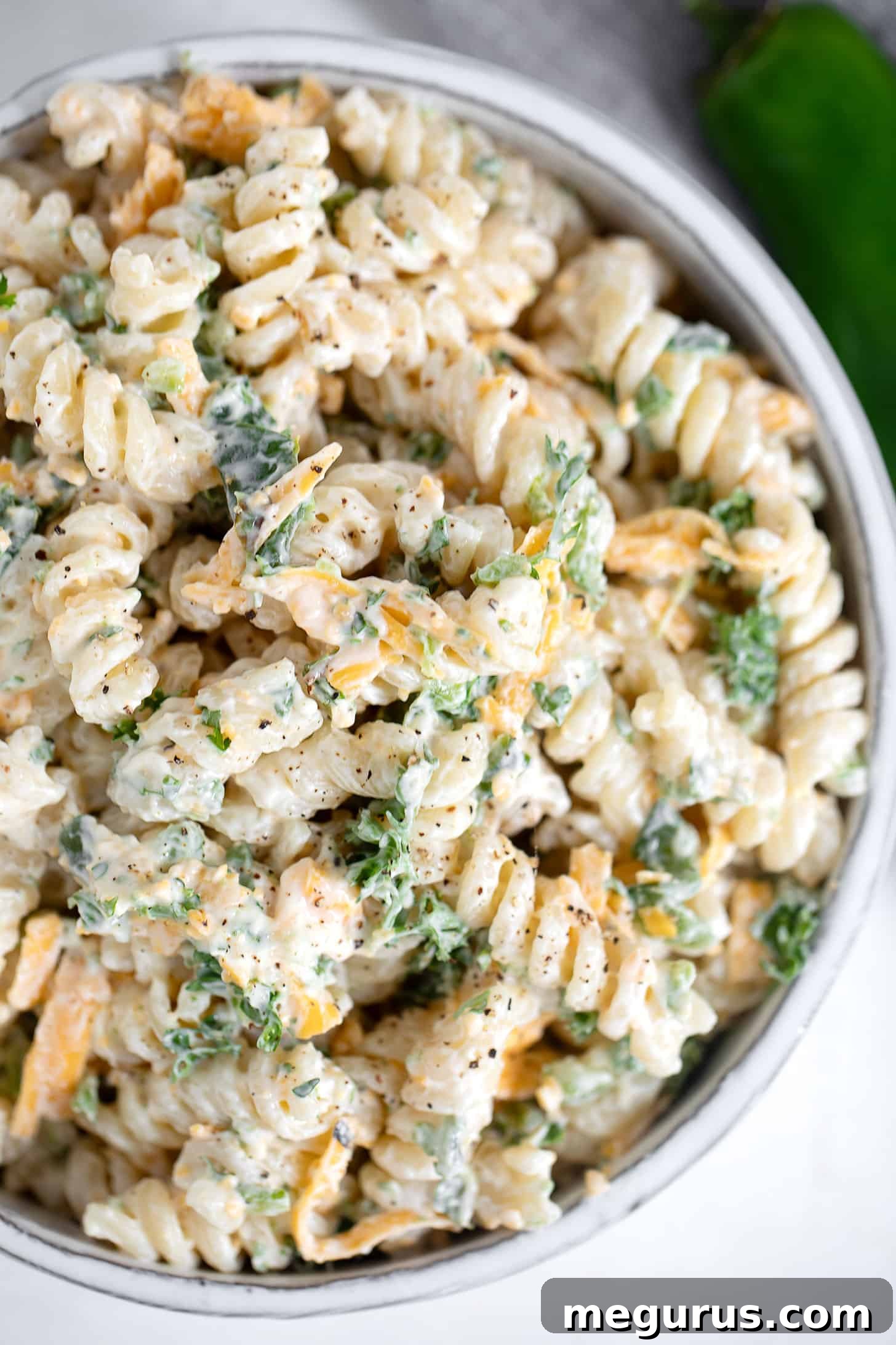 A close-up shot of the finished Jalapeño Popper Pasta Salad in a bowl, garnished with fresh parsley.