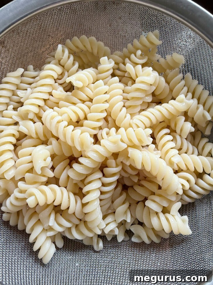 Cooked rotini pasta being drained in a strainer.