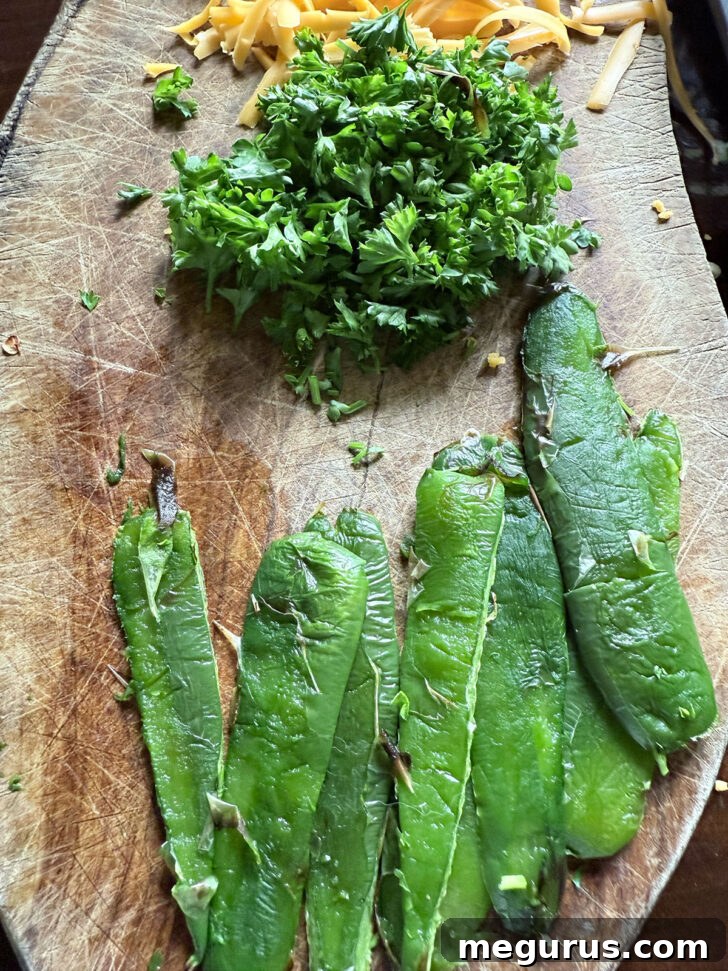 Roasted jalapeños, fresh parsley, and shredded cheddar cheese on a cutting board, prepared for the salad.