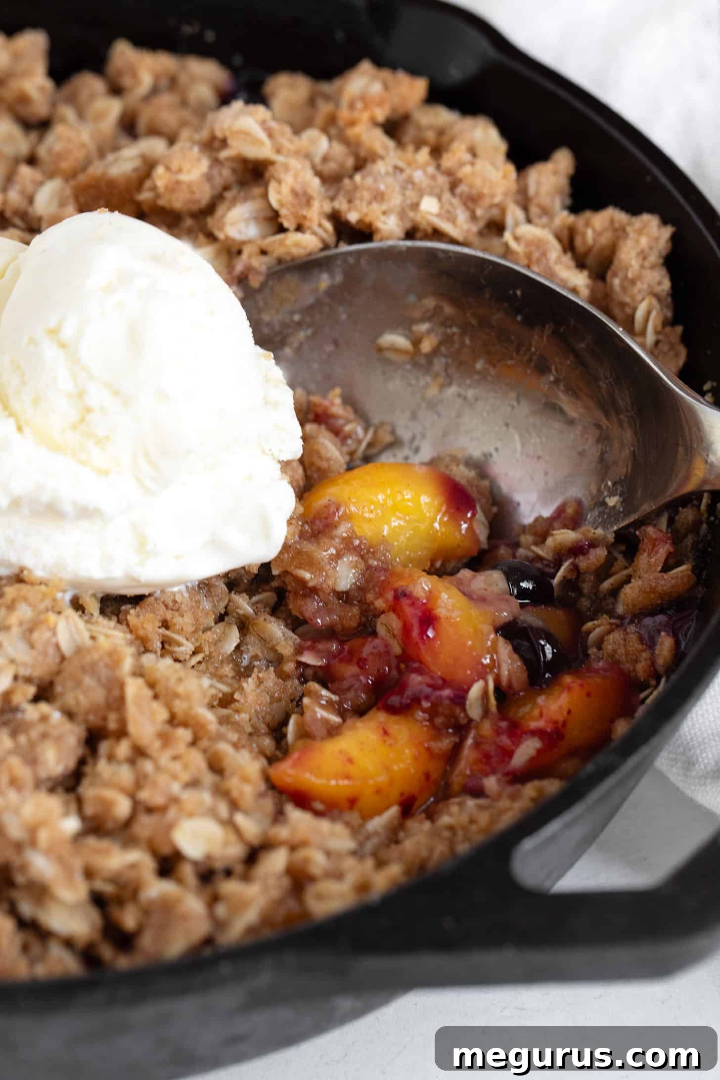 Close-up of a bubbling peach blueberry crisp, hot out of the oven, with a thick crisp topping.