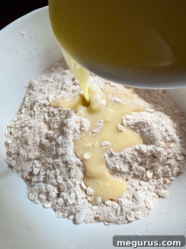 Adding melted butter to a bowl containing dry crisp topping ingredients.