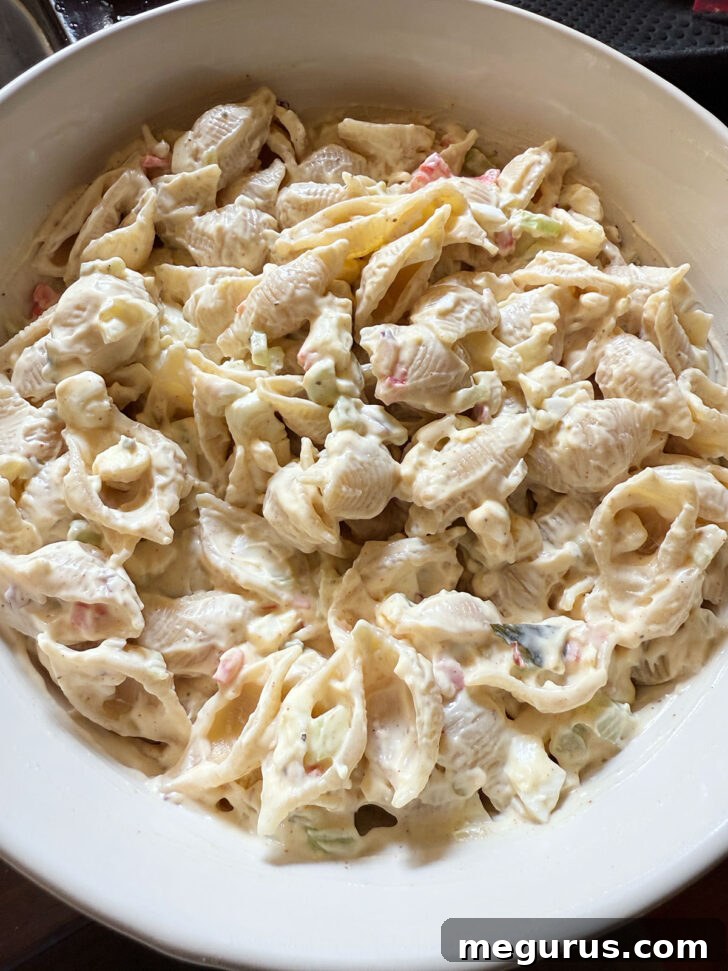 The finished creamy shell pasta salad in a serving bowl, garnished with fresh parsley.