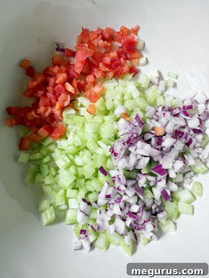 Finely diced bell pepper, celery, and red onion in a large mixing bowl, ready for other ingredients.