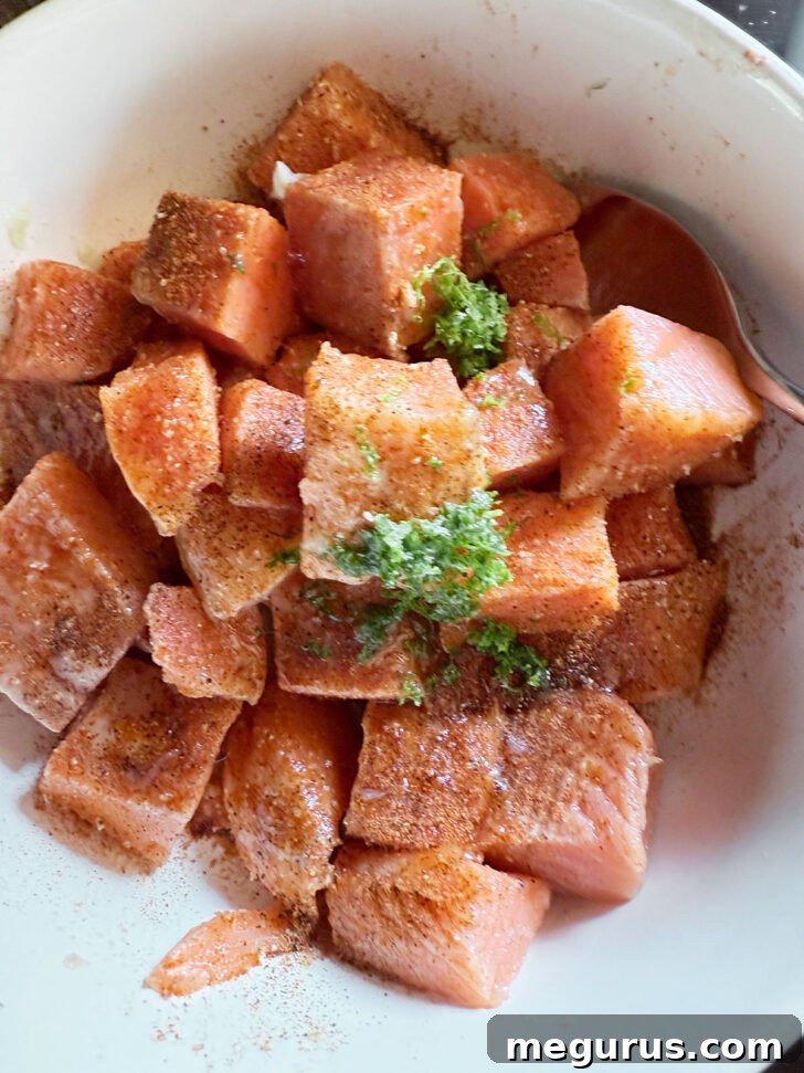 Cubed salmon in a bowl seasoned with chili lime spices.