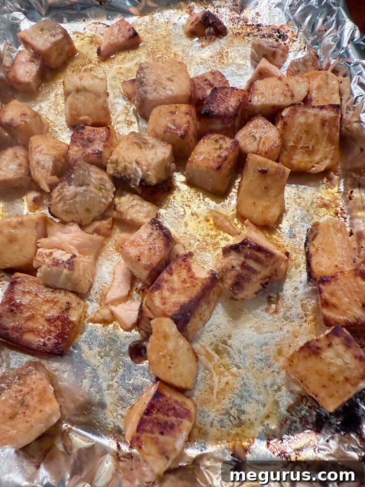 Cooked, browned chili lime salmon cubes on a baking sheet.