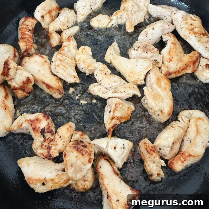 Chicken breast pieces browning beautifully in a hot skillet, signaling the start of a flavorful dish.