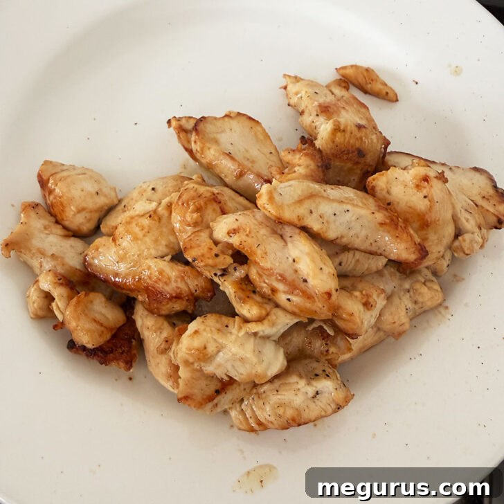 Perfectly browned chicken breast pieces removed from the skillet and resting on a plate, ready for later reintroduction.