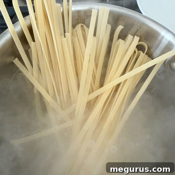 Fettuccine being carefully added to a pot of vigorously boiling water, preparing for an al dente finish.