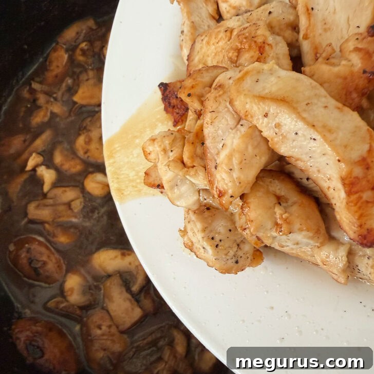 The browned chicken breast pieces are carefully returned to the skillet, joining the rich, simmering Marsala sauce.