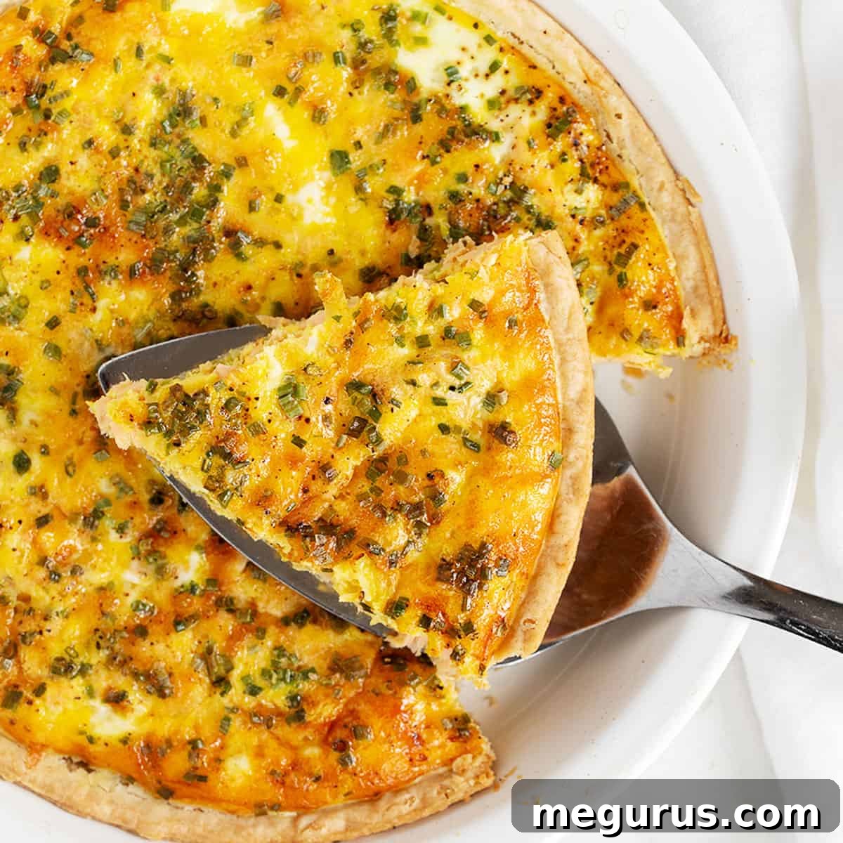 Salmon quiche in pie dish with a sliced on server.