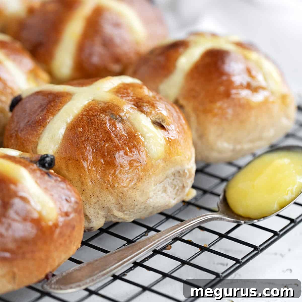 Lemon Hot Cross Buns on a cooling rack, with bright lemon glaze.