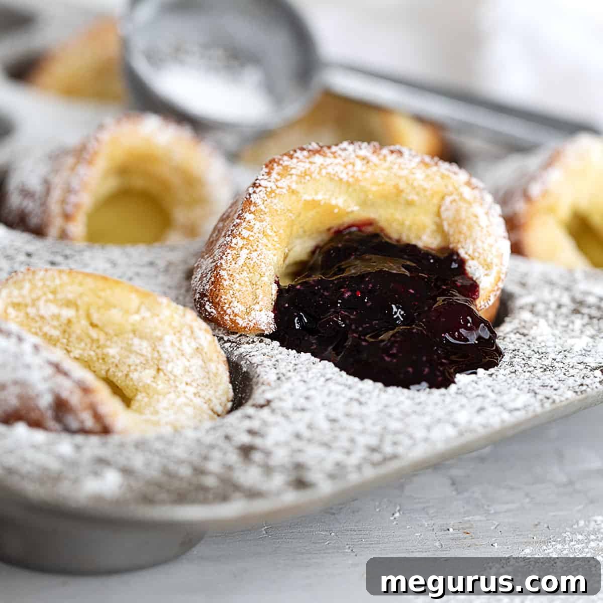 Mini Dutch Pancakes in a muffin tin, served with warm blueberry sauce.