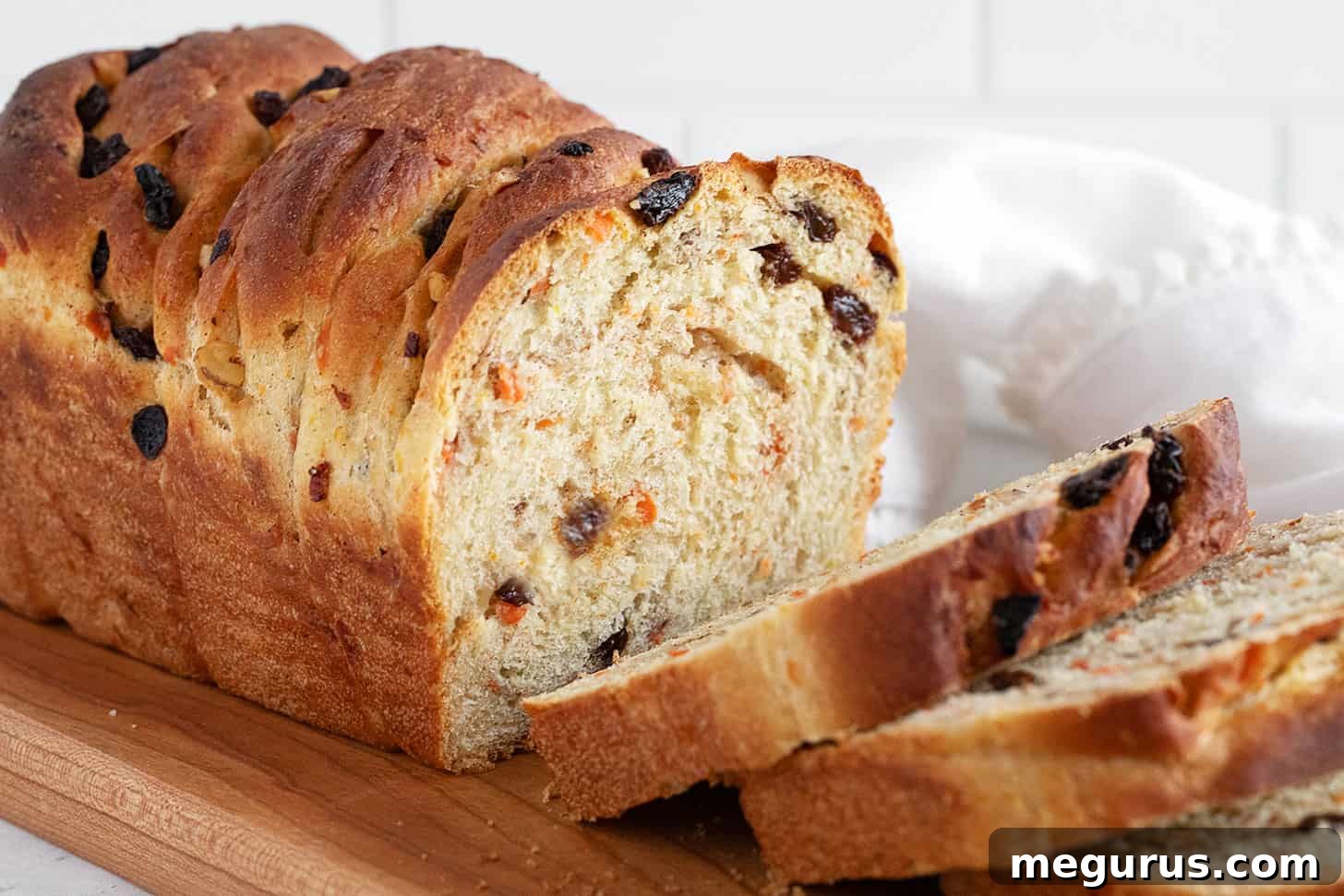 Carrot raisin yeast bread sliced on a cutting board, showcasing its rich texture and fillings.