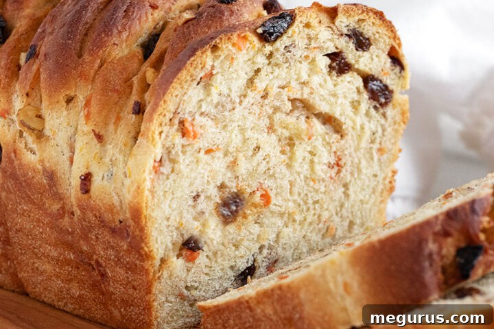 Carrot raisin yeast bread sliced on a cutting board, part of the recipe card image.