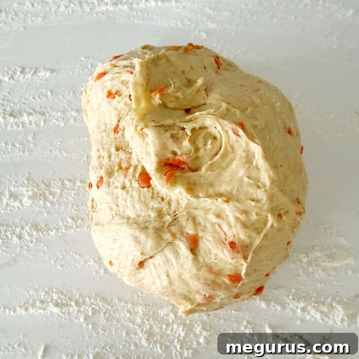 Carrot raisin bread dough on a work surface, ready for shaping.