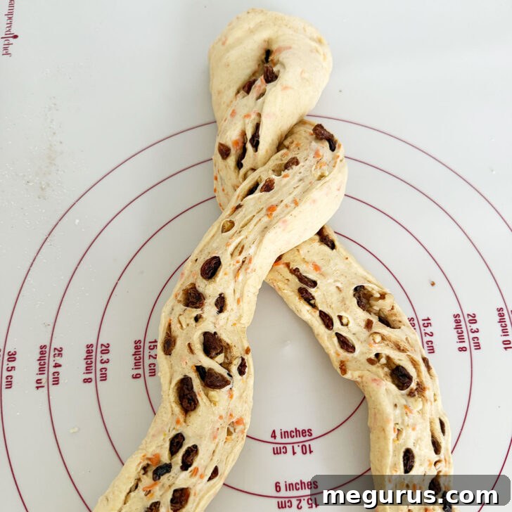 Twisting the two dough strands together to form a braid.