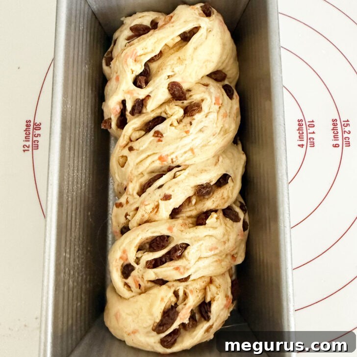 Twisted dough carefully placed in a loaf pan, ready for its final rise.