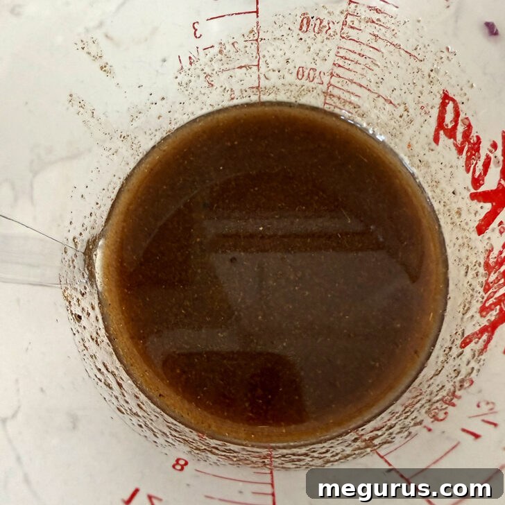 Mexican bean salad dressing mixed up in a measuring cup.