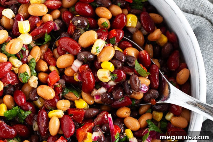 Mexican bean salad in a bowl with a large spoon.