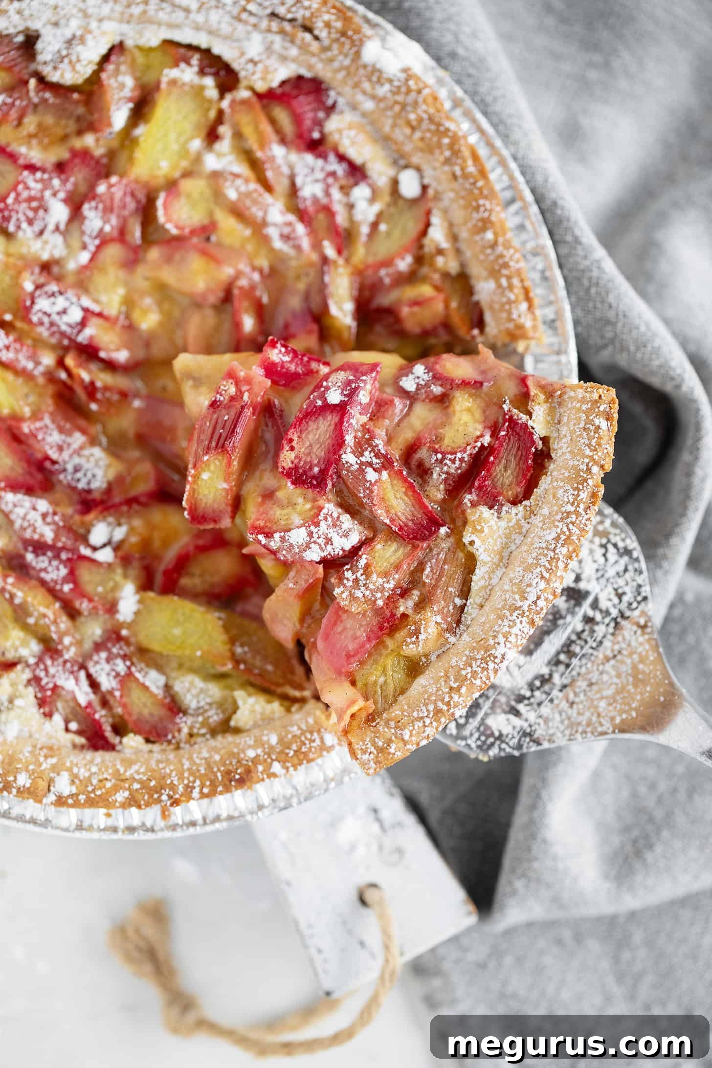 Rhubarb custard pie with a slice on a server.