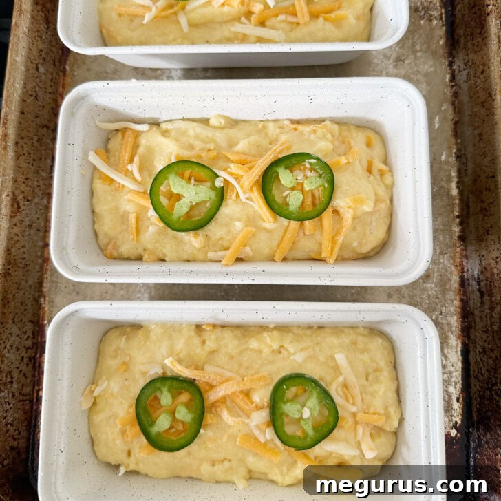 Batter spooned into mini loaf pans and topped with cheddar and jalapeños.