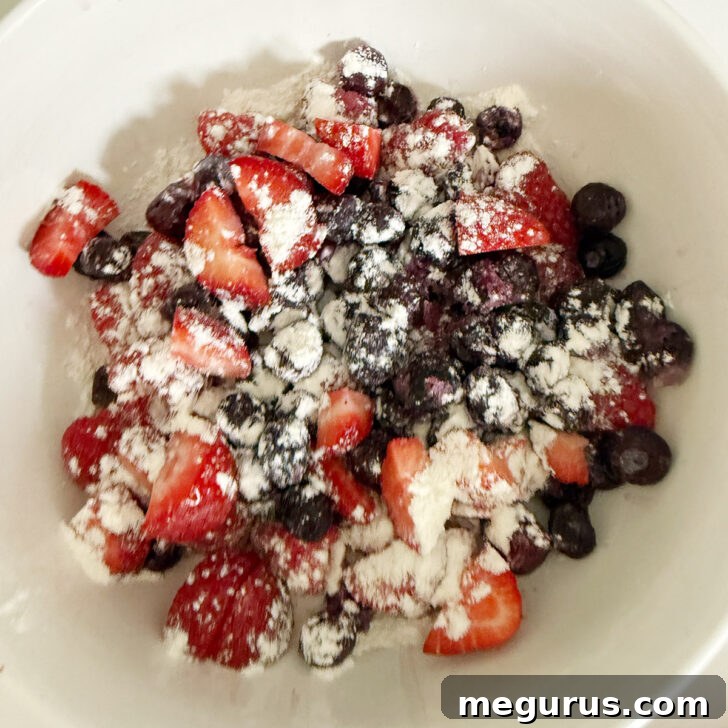 Strawberries, raspberries and blueberries in a bowl with some flour.